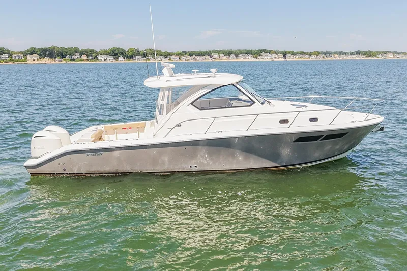  Yacht Photos Pics 2018 Pursuit OS 355 Offshore boat on calm water, with coastal background.