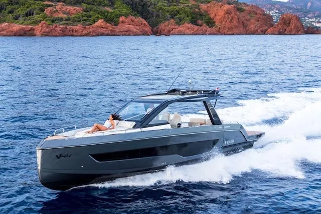  Yacht Photos Pics 2025 Schaefer V44 yacht cruising on blue ocean near rocky coastline.