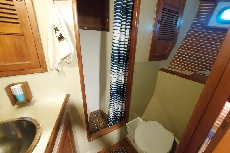 Kallisto Yacht Photos Pics 1982 Kadey-Krogen Krogen 42 Trawler bathroom with wooden cabinetry and striped shower curtain.