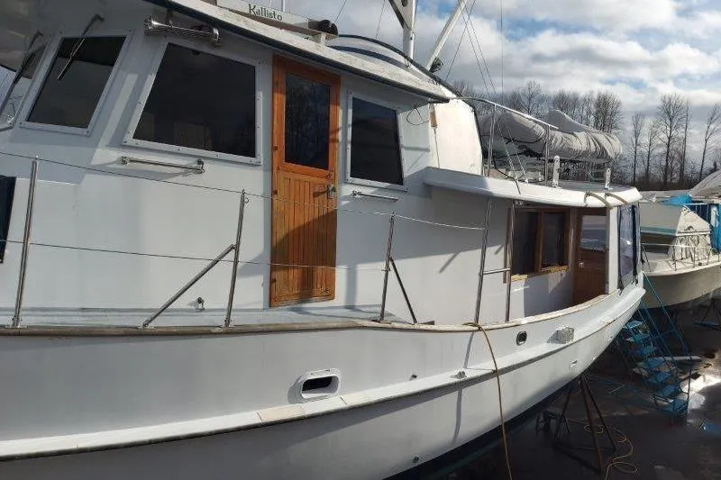 Kallisto Yacht Photos Pics 1982 Kadey-Krogen Pilothouse boat docked, featuring wooden door and windows, under cloudy sky.
