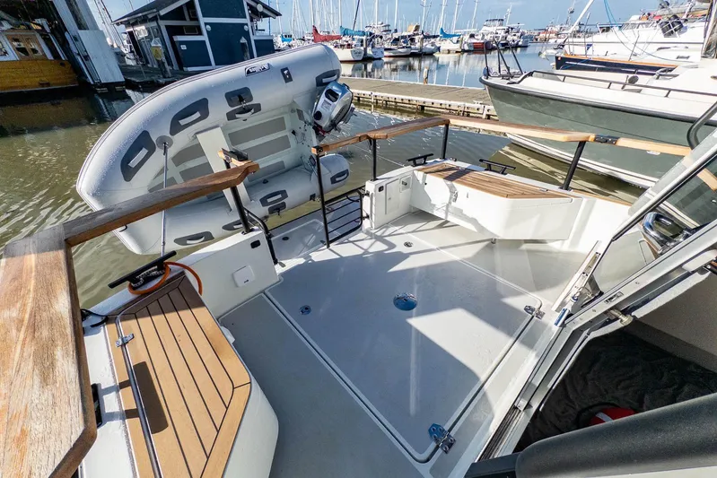  Yacht Photos Pics 2023 Targa 27.2 boat deck with wooden accents and docked inflatable dinghy.