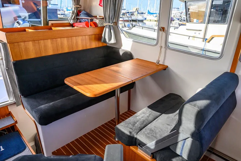  Yacht Photos Pics Interior of 2023 Targa 27.2 boat with wooden table and cushioned seating.