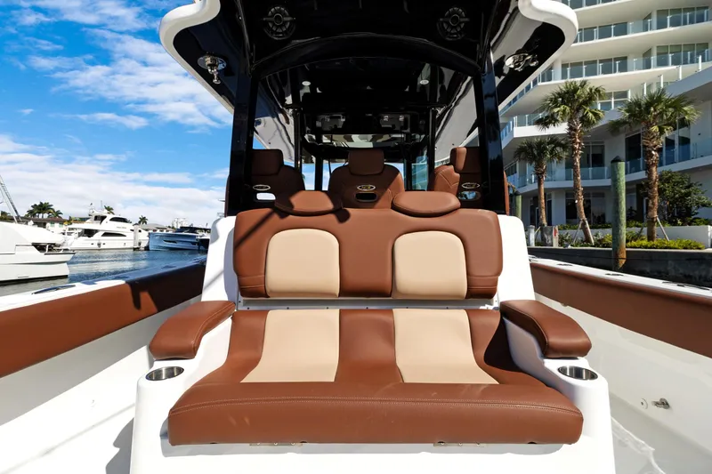  Yacht Photos Pics 2023 HCB Speciale boat interior with luxurious brown and beige seating, docked near palm trees.