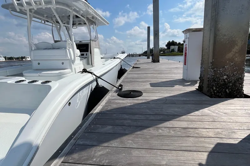 Lunasea Yacht Photos Pics 2023 Yellowfin 32 Offshore boat docked at a wooden pier under a clear sky.