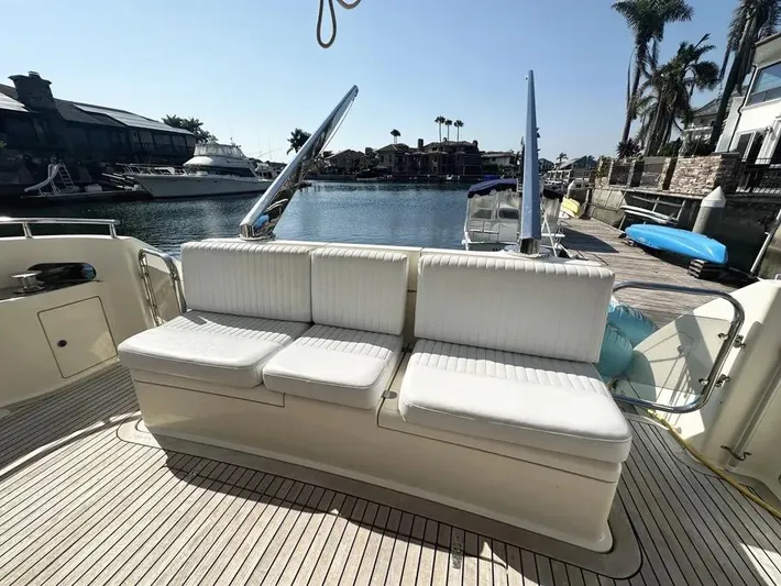 Miss Mazee Yacht Photos Pics 1996 Azimut 54 yacht deck with white seating, docked by a serene waterfront.