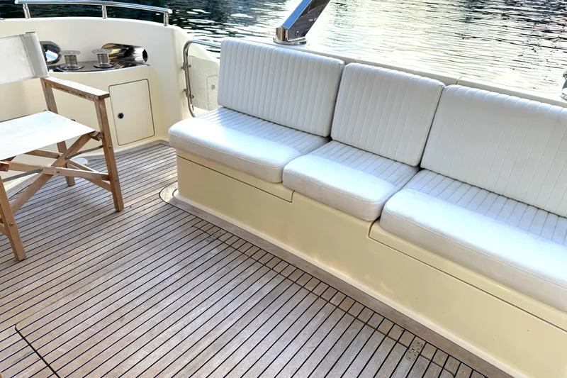 Miss Mazee Yacht Photos Pics Deck seating area on a 1996 Azimut 54 yacht with white cushions and wooden flooring.