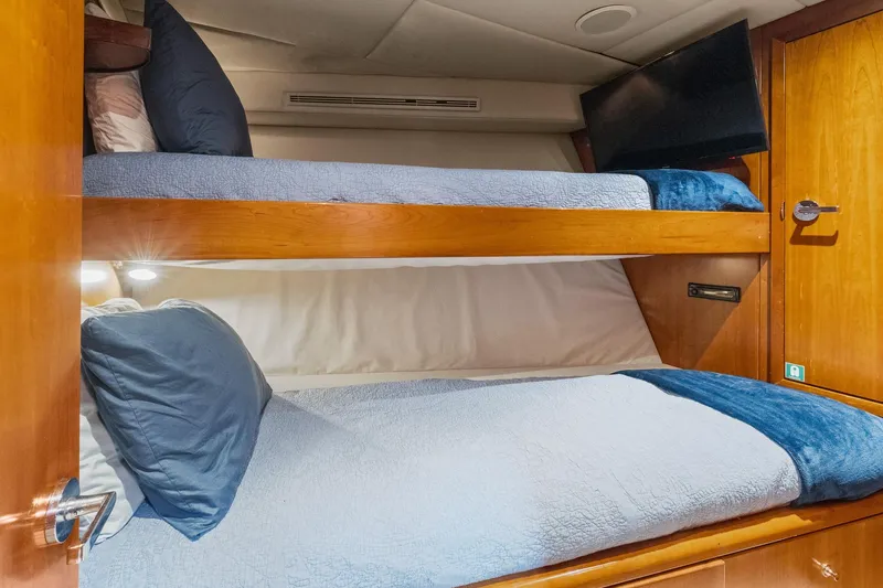  Yacht Photos Pics Bunk beds in 1999 Trinity Yachts Raised Pilothouse, featuring cozy bedding and a wall-mounted TV.