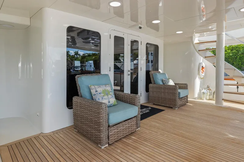  Yacht Photos Pics Luxurious 1999 Trinity Yachts Raised Pilothouse deck with wicker chairs and spiral staircase.