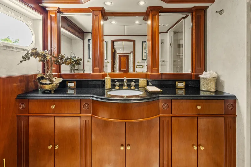  Yacht Photos Pics Luxurious 1999 Trinity Yachts Raised Pilothouse bathroom with elegant wood cabinetry and black countertop.