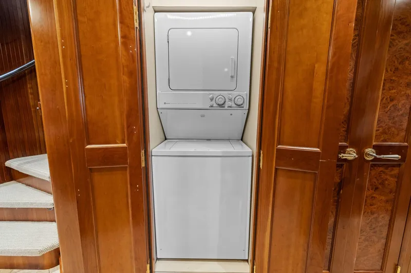  Yacht Photos Pics Stacked washer and dryer in 1999 Trinity Yachts Raised Pilothouse, surrounded by wooden cabinetry.