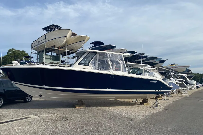  Yacht Photos Pics 2024 Pursuit S 328 Sport boat displayed in a marina, surrounded by other vessels.