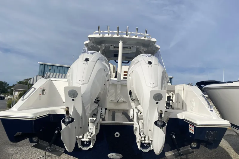  Yacht Photos Pics 2024 Pursuit S 328 Sport boat with dual outboard engines, docked under a clear sky.