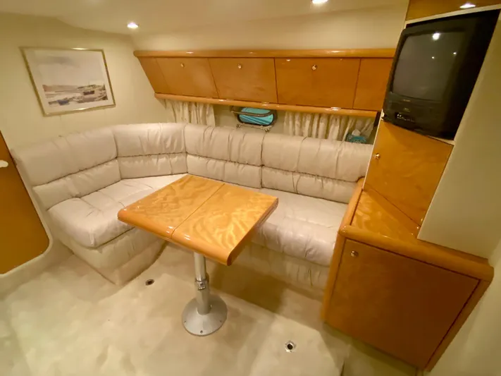 Tude Yacht Photos Pics Interior of 1995 Sunseeker Apache 45 yacht with beige seating, wooden table, and TV.