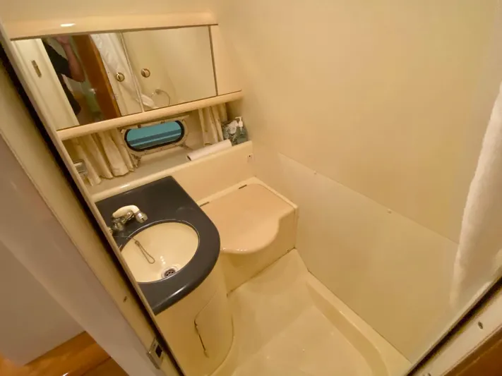 Tude Yacht Photos Pics Compact bathroom in 1995 Sunseeker Apache 45 yacht with sink, toilet, and mirror.