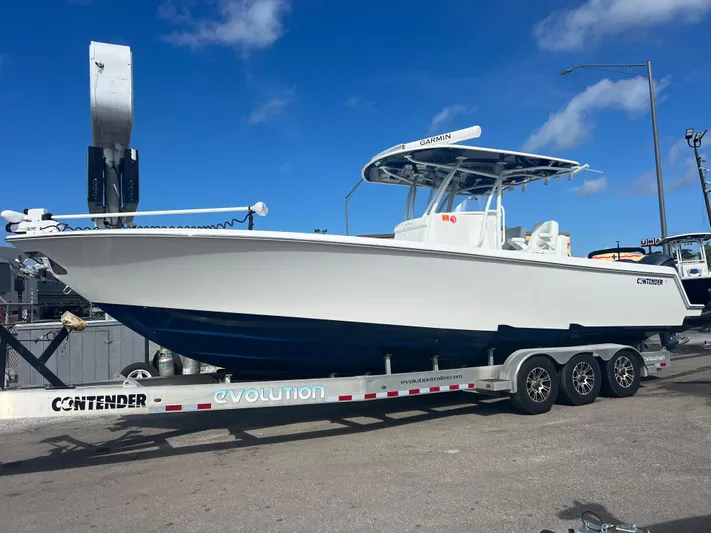  Yacht Photos Pics 2019 Contender 32 ST boat on trailer, white hull, blue bottom, clear sky background.