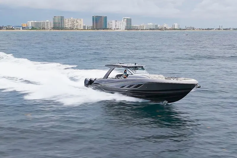  Yacht Photos Pics 2026 Deep Impact 499 Sport boat cruising near city skyline on open water.