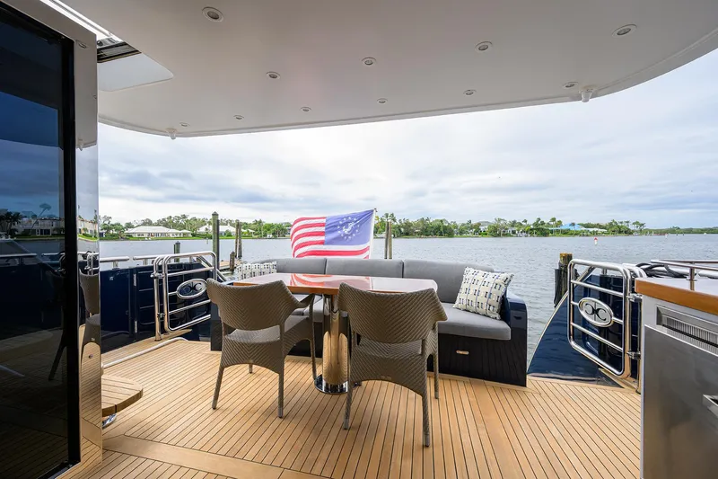 Indigo Yacht Photos Pics Coastal Craft Concord 65 yacht deck with seating, table, and American flag, 2018 model.