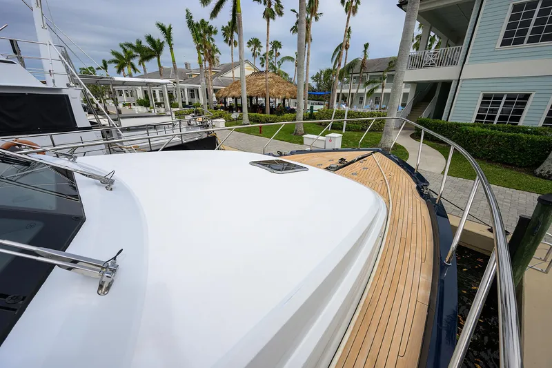 Indigo Yacht Photos Pics Coastal Craft Concord 65 yacht deck, 2018 model, docked near palm trees and waterfront homes.