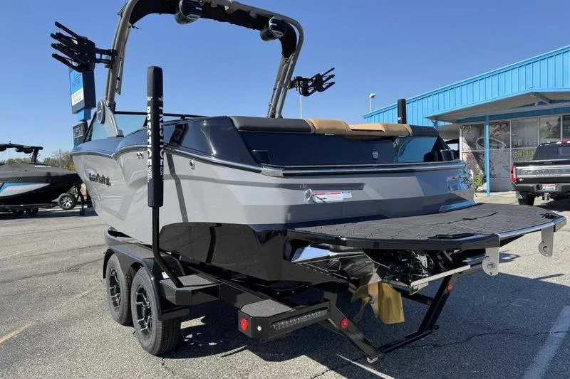 2026 MasterCraft NXT22 boat on trailer, displayed outdoors under clear blue sky.