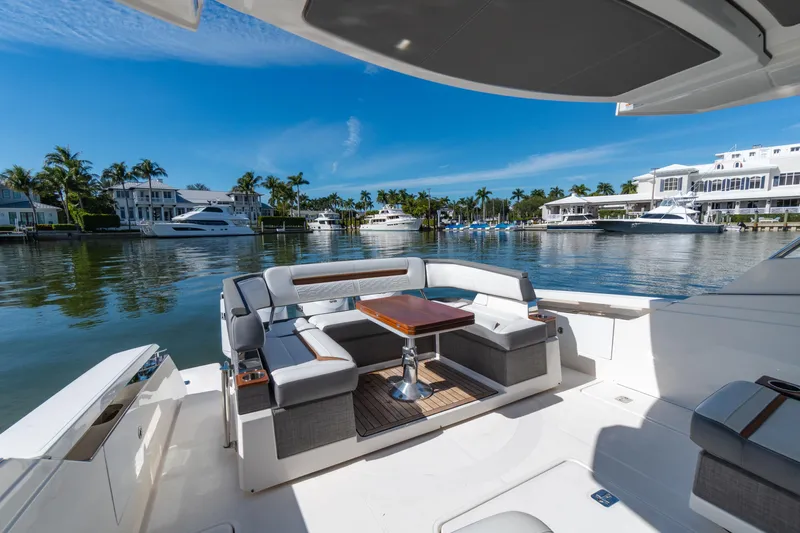  Yacht Photos Pics 2020 Tiara Sport 38 LS yacht interior with luxurious seating and table, docked by waterfront homes.