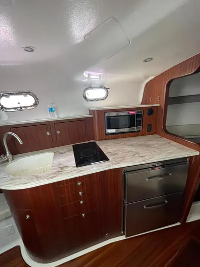No Name Yacht Photos Pics 2019 Pursuit OS 385 Offshore yacht kitchen with modern appliances and wood cabinetry.