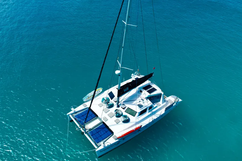 Turquoise Turtle Yacht Photos Pics Aerial view of 2001 Voyage 500 catamaran sailing on clear blue water.