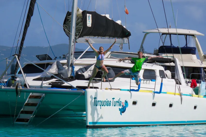 Turquoise Turtle Yacht Photos Pics Two people joyfully jumping off a 2001 Voyage 500 catamaran named "Turquoise Turtle."