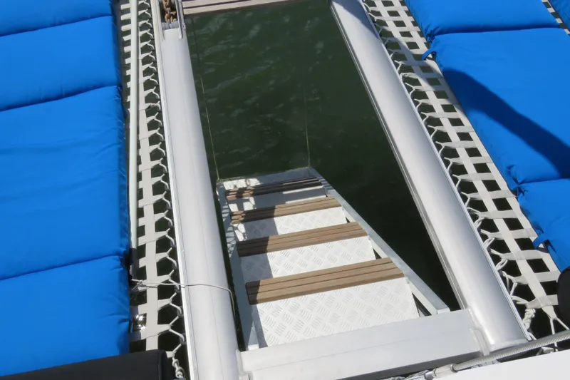 Turquoise Turtle Yacht Photos Pics Catamaran Voyage 500, 2001 model, with blue cushions and a metal ladder over water.