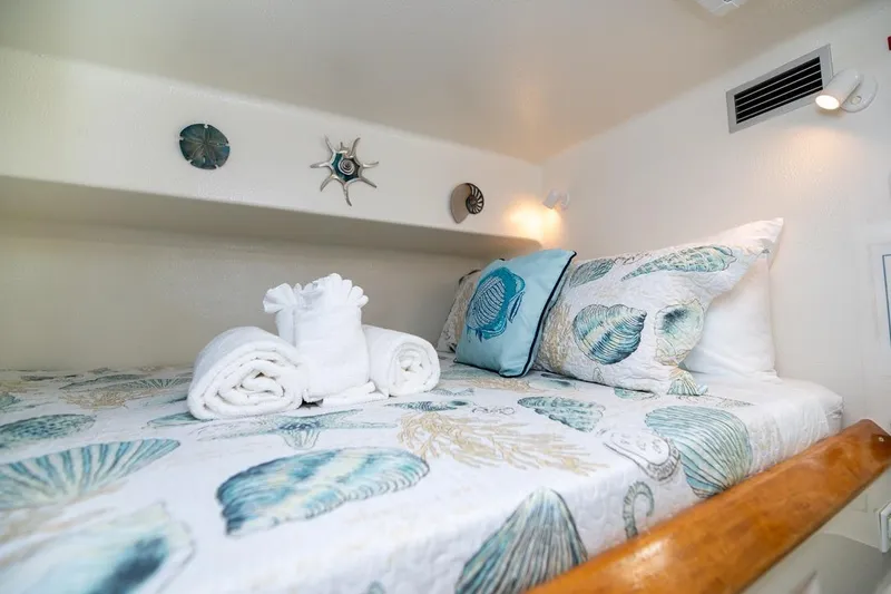 Turquoise Turtle Yacht Photos Pics Cozy cabin interior of 2001 Voyage 500 yacht with seashell-themed bedding and decorative towels.