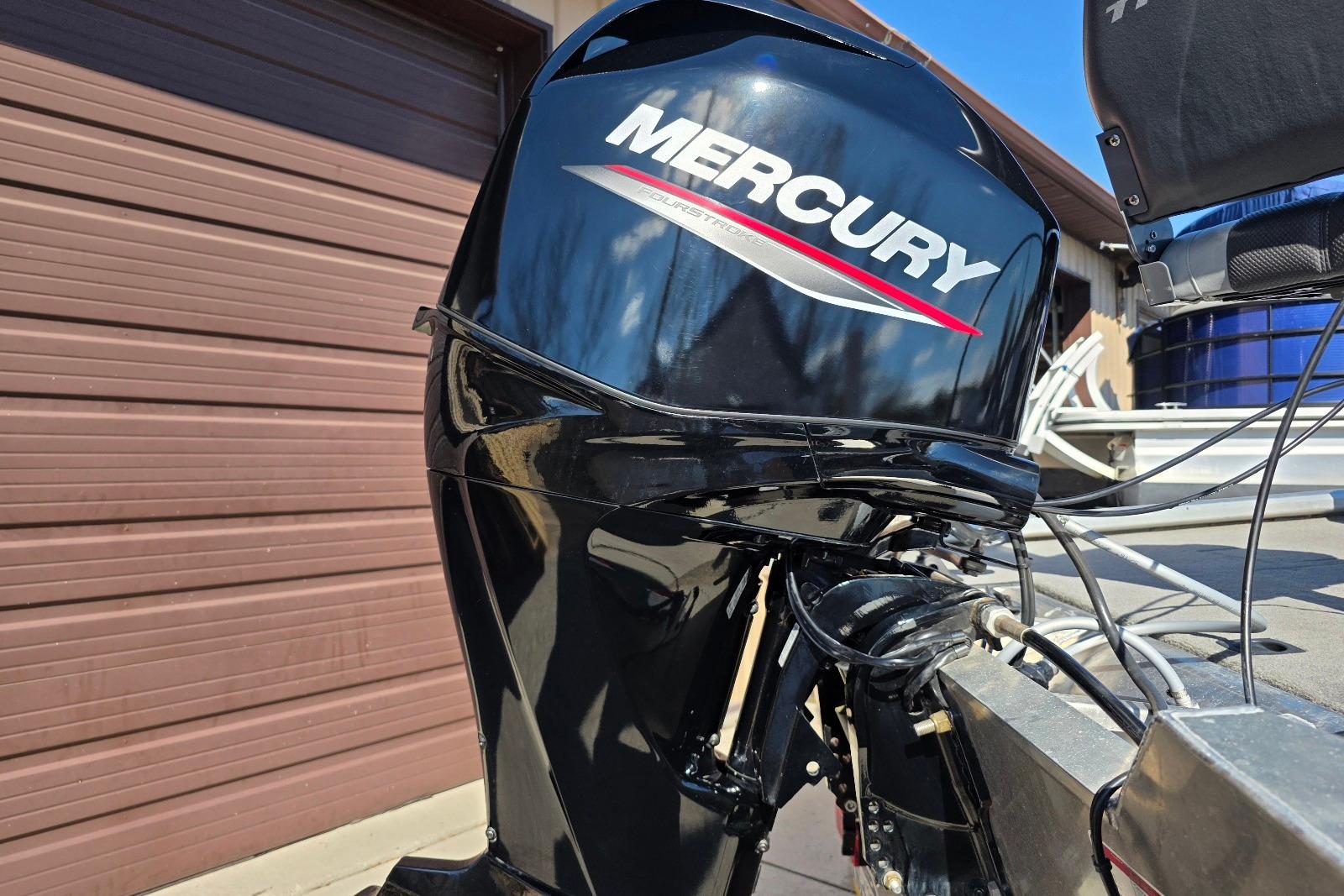 Mercury outboard motor on 2010 Bass Tracker Pro Crappie 175 boat, parked near garage.