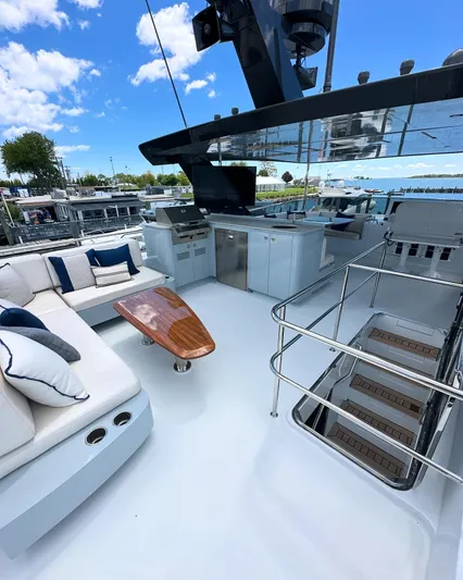  Yacht Photos Pics Luxurious 2023 CL Yachts CLB65 deck with seating, table, and stairs under a clear blue sky.