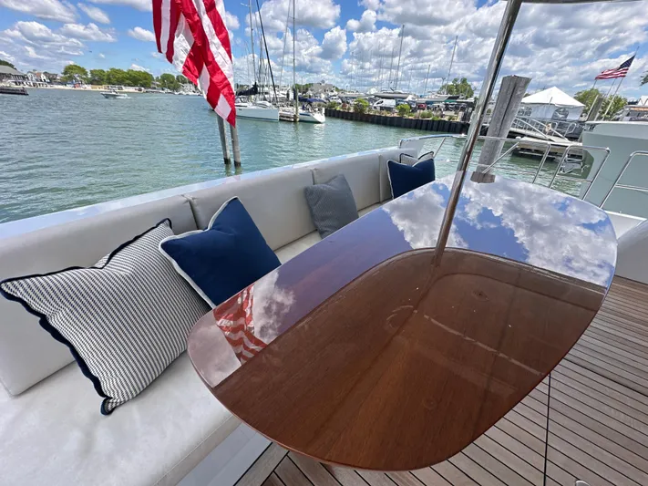  Yacht Photos Pics 2023 CL Yachts CLB65 yacht deck with cushions, wooden table, and American flag.