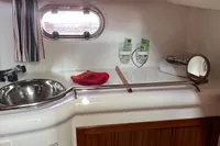1999 Nimbus 380 Carisma yacht bathroom with sink, porthole, and wooden cabinetry.