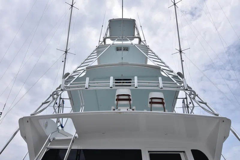 Legacy Yacht Photos Pics 1999 Viking 58 Convertible yacht, viewed from below, showcasing its towering structure against a cloudy sky.