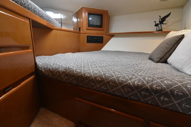 Legacy Yacht Photos Pics 1999 Viking 58 Convertible yacht bedroom with anchor-patterned bedding and wooden cabinetry.