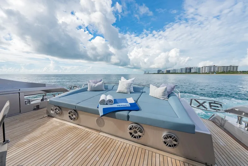 Vintage Yacht Photos Pics Luxurious 2021 Pershing 9X yacht deck with sunbed, ocean view, and coastal skyline.