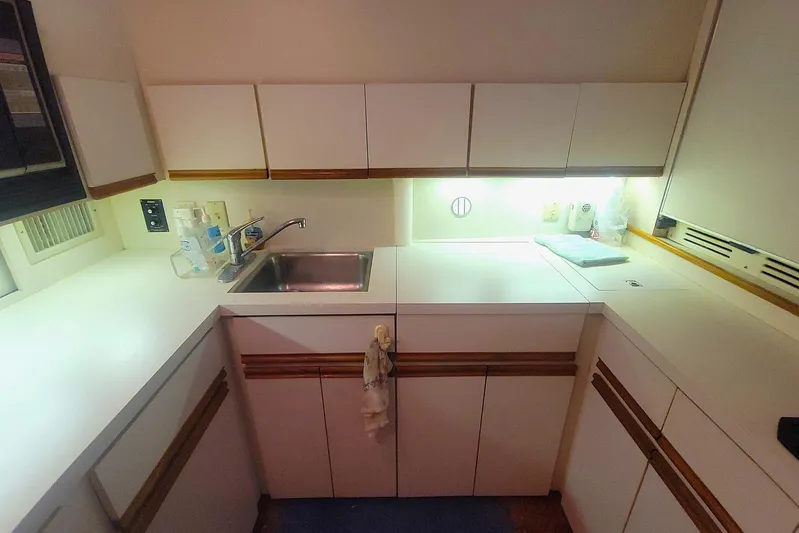 Trophy Hunter Yacht Photos Pics 1989 Bertram 50 Convertible yacht kitchen with sink, white cabinets, and countertop.