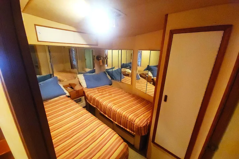Trophy Hunter Yacht Photos Pics 1989 Bertram 50 Convertible cabin with twin beds, striped bedding, and mirrored walls.
