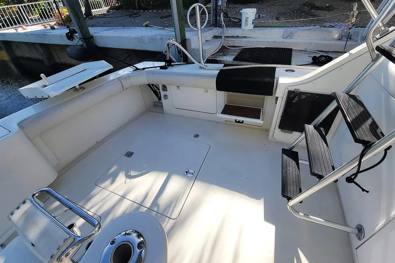 Trophy Hunter Yacht Photos Pics 1989 Bertram 50 Convertible boat deck with seating and ladder, docked by the water.