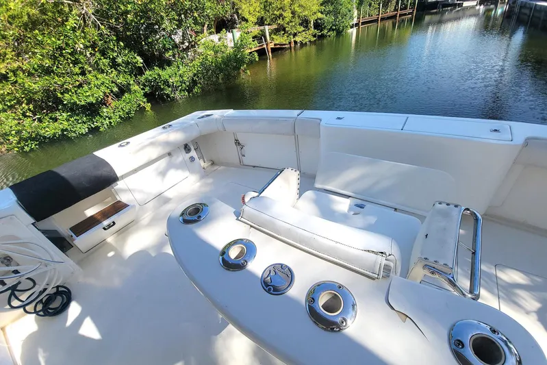Trophy Hunter Yacht Photos Pics 1989 Bertram 50 Convertible yacht deck with fishing rod holders, near lush greenery.