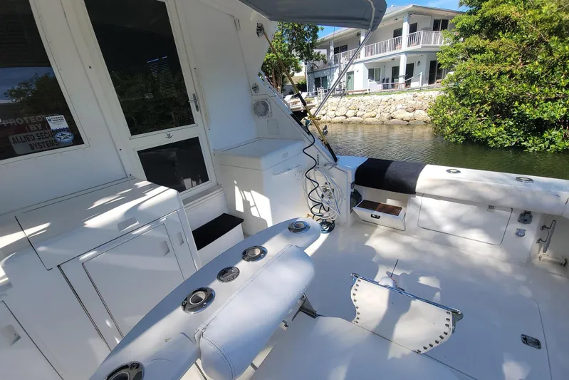 Trophy Hunter Yacht Photos Pics 1989 Bertram 50 Convertible boat deck with fishing rod holders and seating, near waterfront homes.