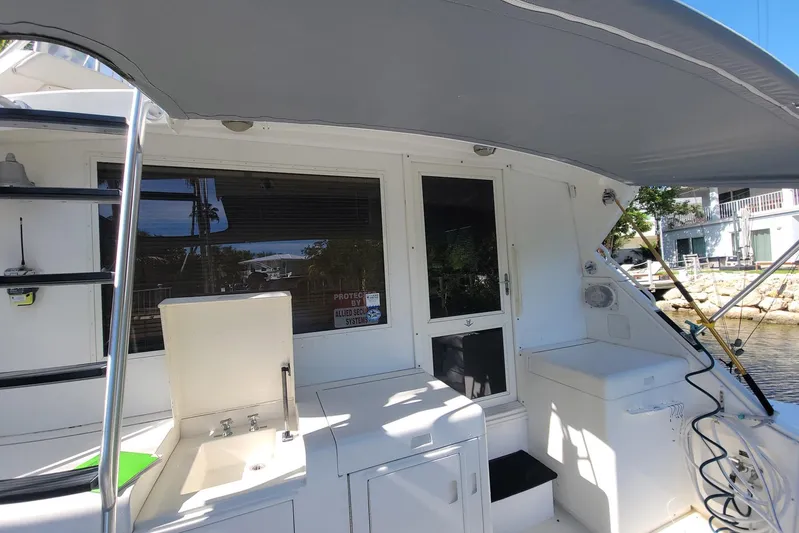 Trophy Hunter Yacht Photos Pics 1989 Bertram 50 Convertible yacht deck with sink and ladder, docked by waterfront homes.