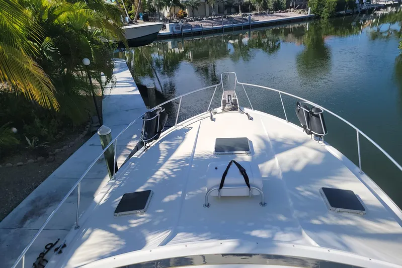 Trophy Hunter Yacht Photos Pics 1989 Bertram 50 Convertible yacht docked by a serene canal, surrounded by lush greenery.