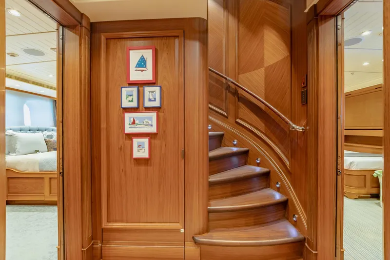 Shadowl Yacht Photos Pics Luxurious yacht interior with curved wooden staircase and framed nautical art.