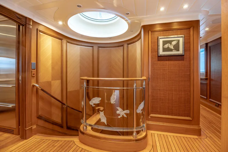 Shadowl Yacht Photos Pics Luxurious yacht interior with wooden paneling, glass railing, and framed bird artwork.