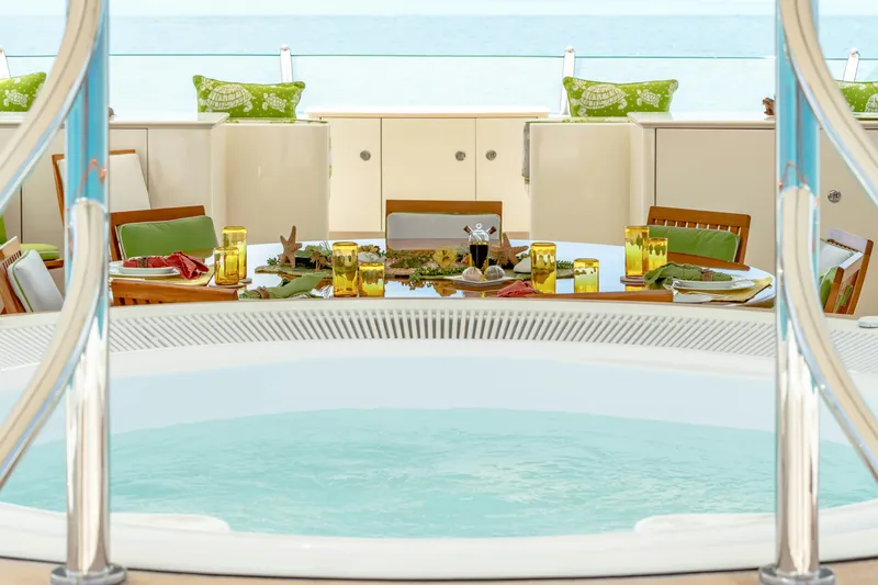 Shadowl Yacht Photos Pics Luxurious yacht deck with jacuzzi and elegant dining setup, featuring green and yellow accents.