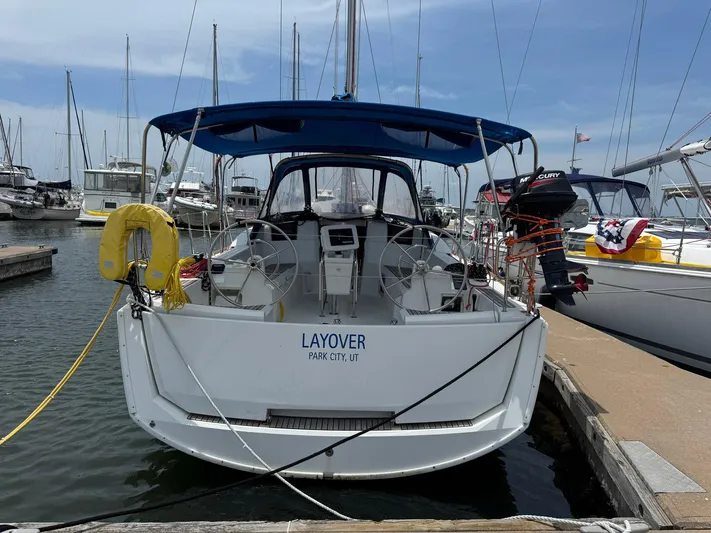 Layover Yacht Photos Pics 2018 Jeanneau Sun Odyssey 389 sailboat docked at marina, rear view with blue canopy.