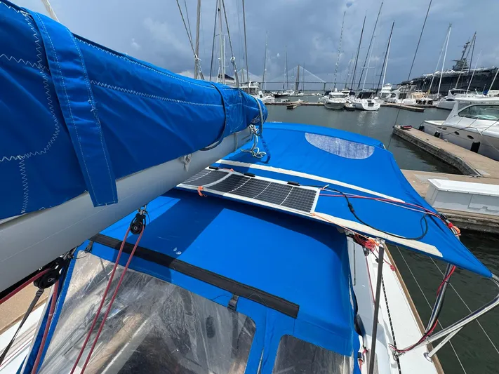 Layover Yacht Photos Pics Jeanneau Sun Odyssey 389 sailboat with blue cover and solar panel, docked in marina.