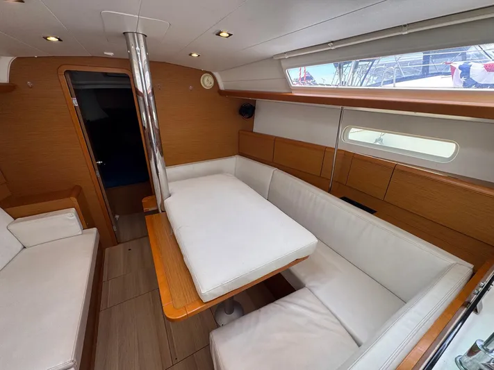 Layover Yacht Photos Pics Interior of 2018 Jeanneau Sun Odyssey 389 yacht with white seating and wooden accents.