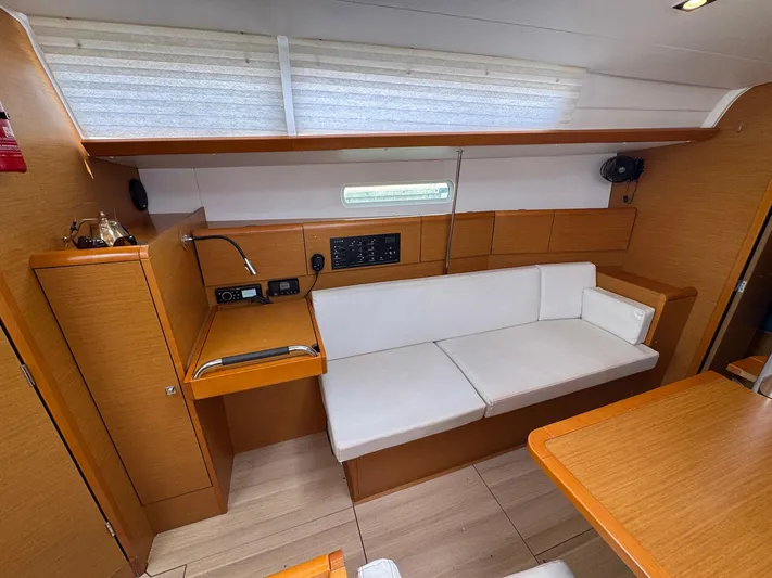 Layover Yacht Photos Pics Interior of 2018 Jeanneau Sun Odyssey 389 sailboat with white seating and wooden cabinetry.